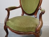 une vieille chaise dont l'assise est recouverte de tissu vert, dans une pièce