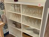 une étagère sur laquelle sont posés des verres et des assiettes, dans une pièce