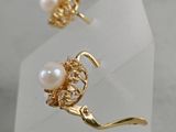 gold plated earrings with pearls and crystals on a white surface