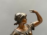 statue en bronze représentant une femme le bras levé vers le ciel