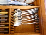 de nombreuses cuillères et couteaux dans un tiroir avec d'autres ustensiles