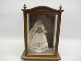 une poupée ancienne dans une vitrine, sur fond blanc