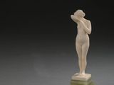 statue d'une femme debout sur un socle vert, sur fond noir