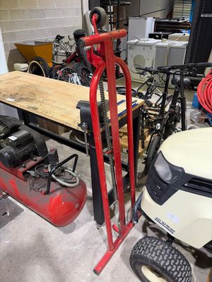 une photo d'un garage avec une tondeuse à gazon et un établi