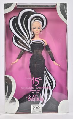 La poupée Barbie se trouve dans une boîte, vêtue d'une robe noire et blanche.