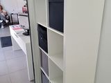 a white book shelf with a black bin on it