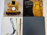 plusieurs livres posés sur une table, à côté d'une horloge et d'un stylo