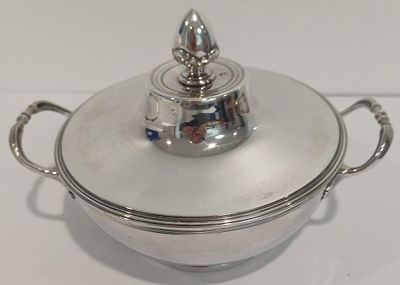 une casserole en argent avec un couvercle, posée sur une table blanche