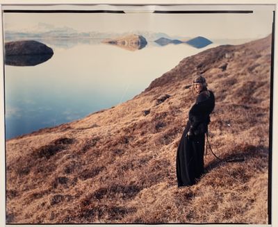 une femme qui se tient debout sur une colline au bord de l'eau