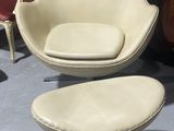 une image représentant une chaise et un pouf dans une pièce où se trouvent plusieurs chaises