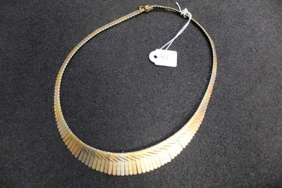 necklace made of gold colored metal with a white tag on a black surface