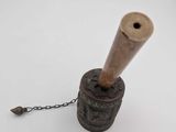 a small wooden pipe on a chain on a white surface