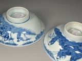 pair of blue and white bowls with horses on them sitting on a table