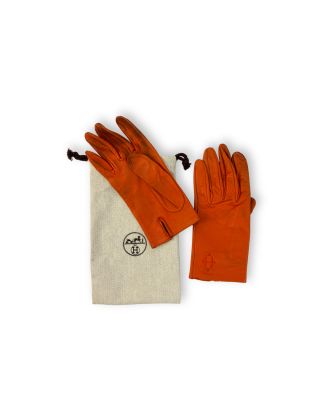 une photo d'une paire de gants en cuir orange accompagnée d'un sac de rangement