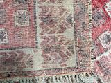 a red and white rug on the floor next to a blue chair