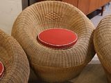 three wicker chairs with red cushions sit in a room