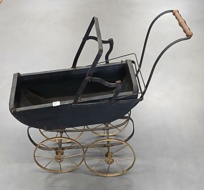 une poussette noire avec une poignée en bois posée sur un sol gris