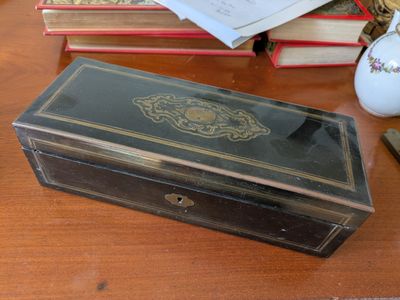 a small wooden box sitting on a table next to a pile of books