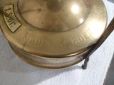 une plaque en laiton munie d'une poignée posée sur une table blanche