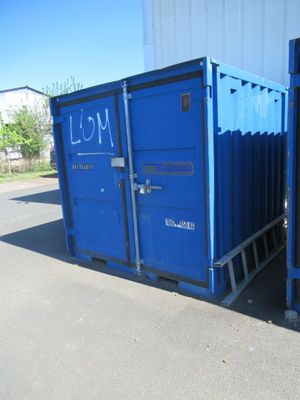 deux conteneurs d'expédition bleus placés l'un à côté de l'autre contre le mur d'un immeuble
