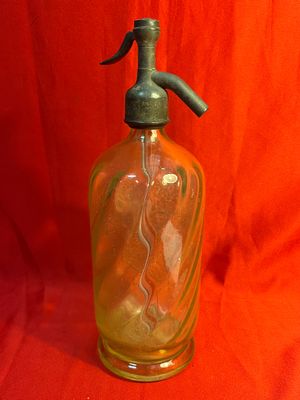 une bouteille en verre munie d'un bec verseur en métal, posée sur un tissu rouge