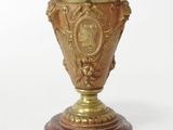 a gold vase sitting on top of a marble base