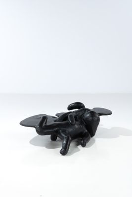 une sculpture noire représentant une abeille posée sur une surface blanche