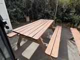 une table de pique-nique en bois avec deux bancs dans le jardin derrière la maison