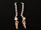 a pair of gold and diamond earrings on a black background