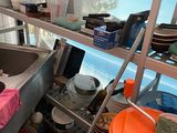 a kitchen with a sink and a shelf full of pots and pans
