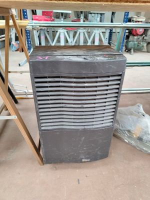 a small air conditioner sitting on the floor next to a chair