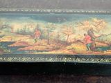 une boîte noire ornée d'une peinture, posée sur une table
