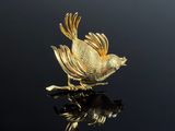 an image of a gold bird sitting on top of a black surface