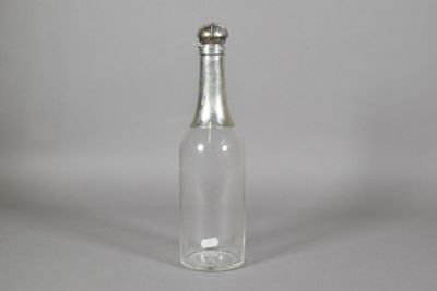 une petite bouteille en verre avec un bouchon argenté posée sur une table