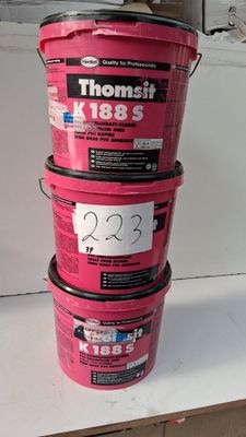 trois seaux de peinture rose posés sur un plan de travail blanc