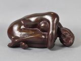 bronze sculpture of a woman laying on her back on a gray surface