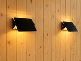 deux lampes noires fixées à un mur en bois dans une pièce aux murs lambrissés