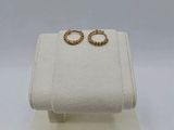 a pair of gold hoop earrings on a white display stand