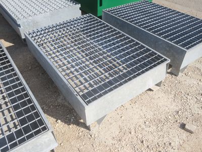 trois grilles métalliques posées par terre à côté d'un conteneur vert