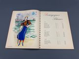 un livre ouvert sur lequel figure le dessin d'une femme en robe bleue