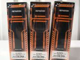 three boxes of black and orange toothbrushes sitting on a white surface