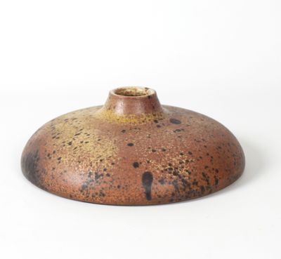 un vase brun et noir posé sur une surface blanche
