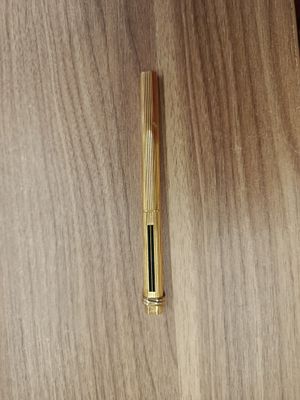 un stylo posé sur une table en bois, à côté d'une tasse
