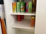 a white cupboard with cans and cans of soda on it