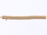 a close up of a gold bracelet on a white surface