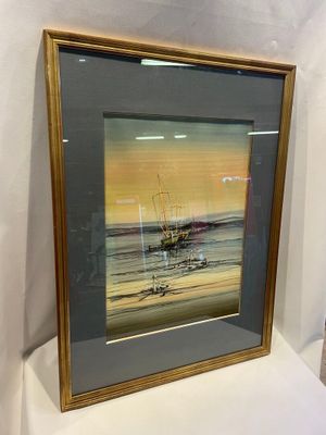 painting of a boat on the water in a frame on a table