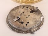 a silver clock on a table next to a glass of water