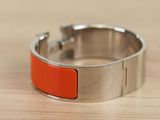 an orange and silver bracelet sitting on top of a wooden table