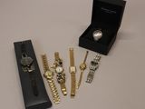 trois montres et un coffret à montres sont posés sur une table