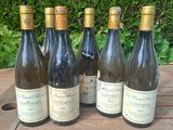 six bottles of wine are lined up on a wooden table